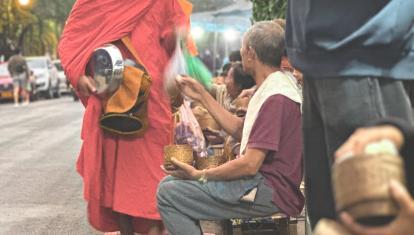 Laotian monk walking down street to accept offerings