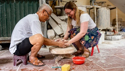Local Vietnamese man showing tourist how to throw pottery