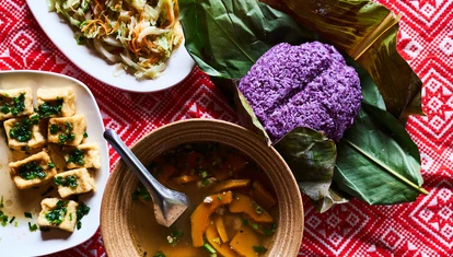 Traditional Vietnamese meal including pumpkin soup, purple rice and a brightly coloured tablecloth