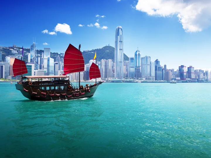 Junk boat with red flags crossing Hong Kong harbour 