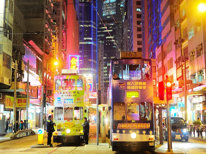 Trams at night lit up by neon signs 