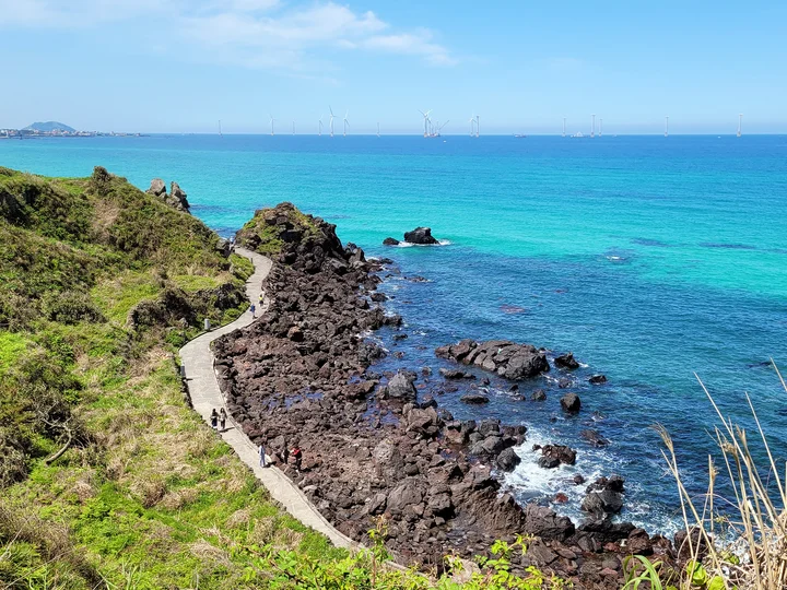 Hikers walk along the Handam Coast trail surrounded by azure waters in Jeju island