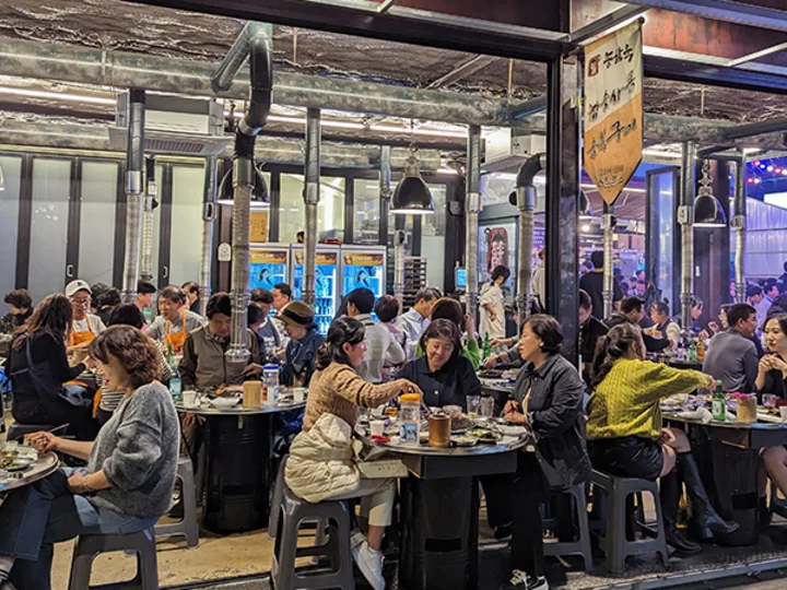 Korean BBQ restaurant with customers dining at tables, industrial decor, and large windows