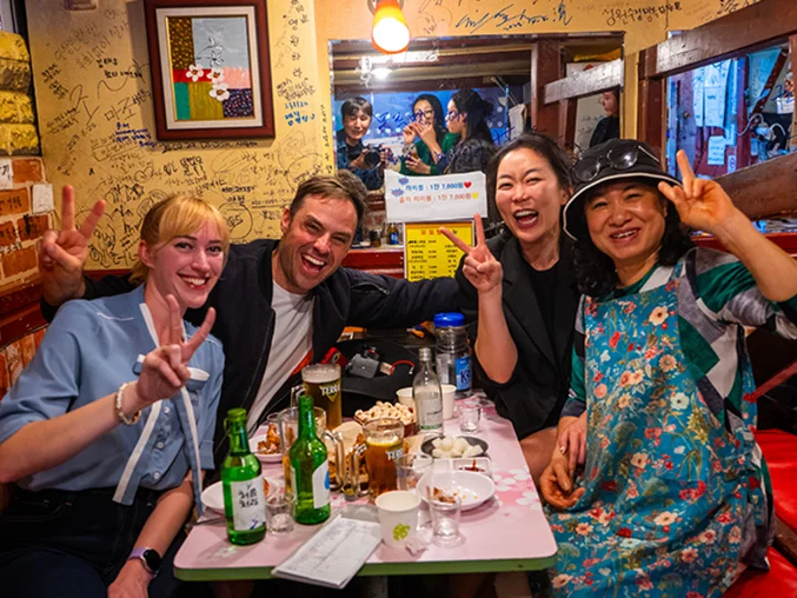 A group of people posing with peace signs at a table filled with food and drinks