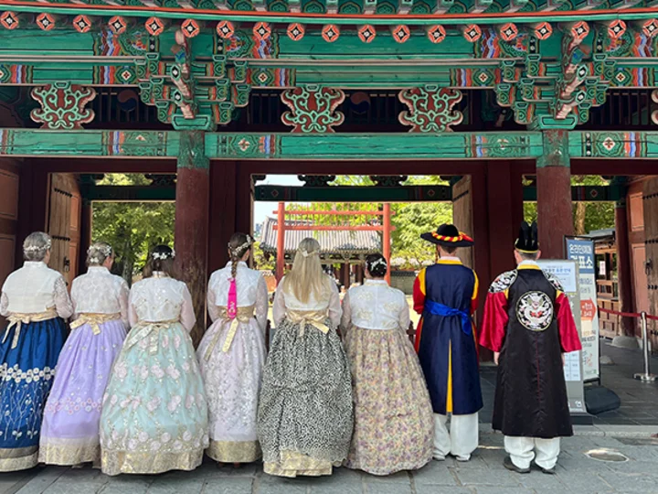 A group of people in traditional Korean hanbok attire outside an ornate gate in Jeonju
