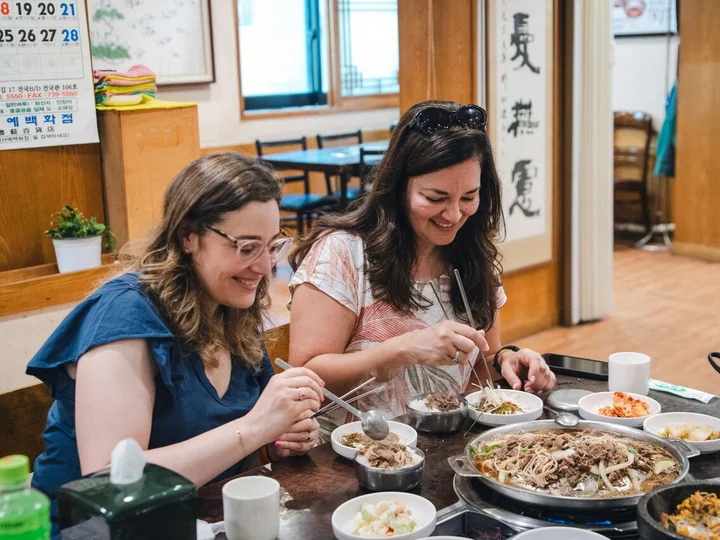 Two women enjoying authentic Korean food on a small group tour