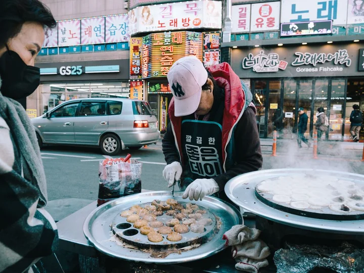 Man preparing street food on bustling South Korean street