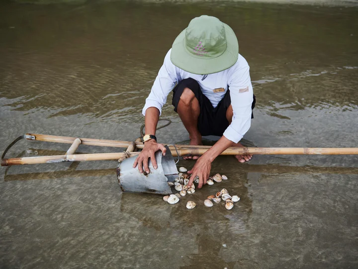 Man in Con Dao beachcoming clambs