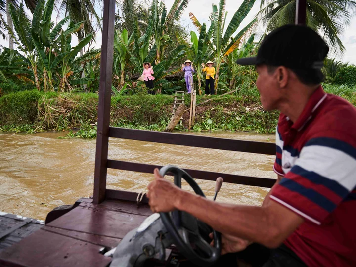 Vietnamese women waving at an incoming man on a boat in the Mekong Delta