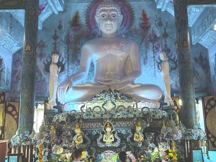 Family kneeling in front of giant buddha statue