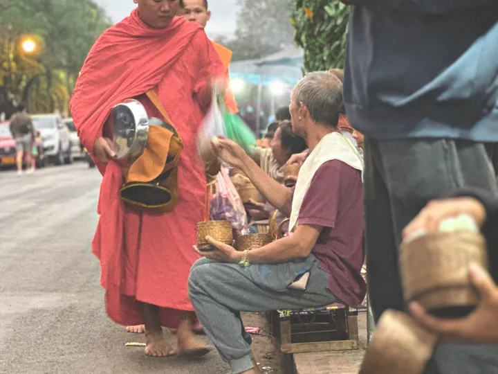 Laotian monk walking down street to accept offerings