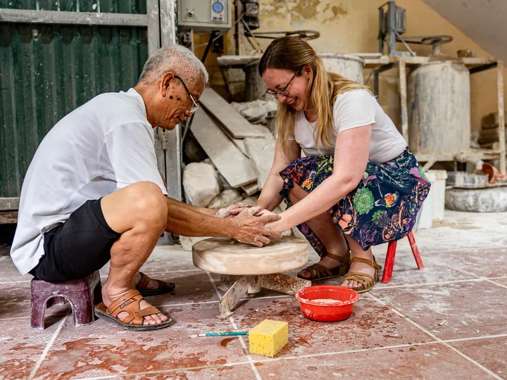 Local Vietnamese man showing tourist how to throw pottery
