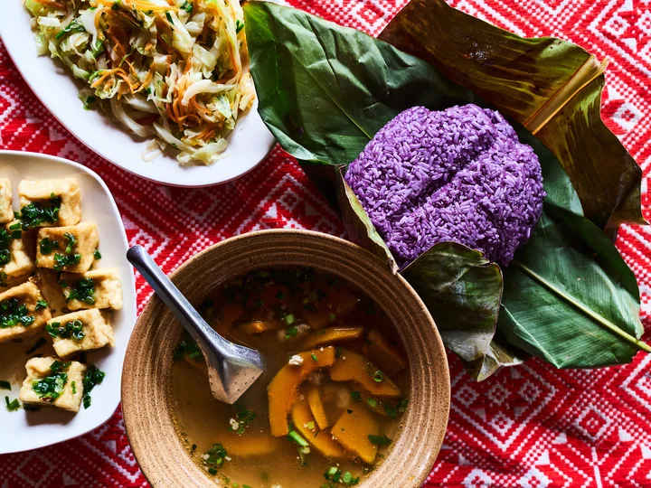 Traditional Vietnamese meal including pumpkin soup, purple rice and a brightly coloured tablecloth