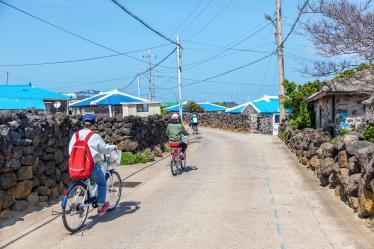 Two people cycling along a quiet street in Udo Island