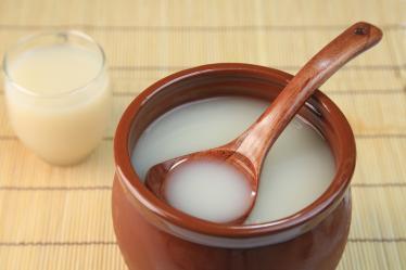Creamy white Makgeolli rice wine in brown cup with spoon