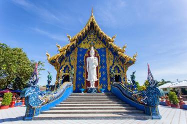 Blue Temple with white Buddha statue at top of stairs 