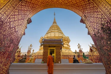 Girl looking up at gilded arch in front of golden temple in Chiang Mai 
