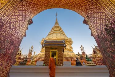 Girl looking up at gilded arch in front of golden temple in Chiang Mai 